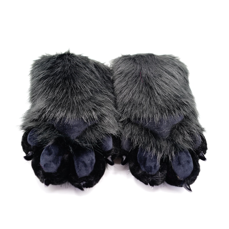 May include: A pair of black furry slippers shaped like animal paws. The slippers have three toes and a black, plush fur covering.
