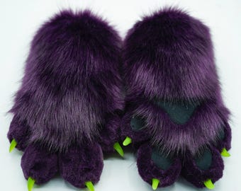 May include: A pair of purple furry paw hand warmers with green claws.