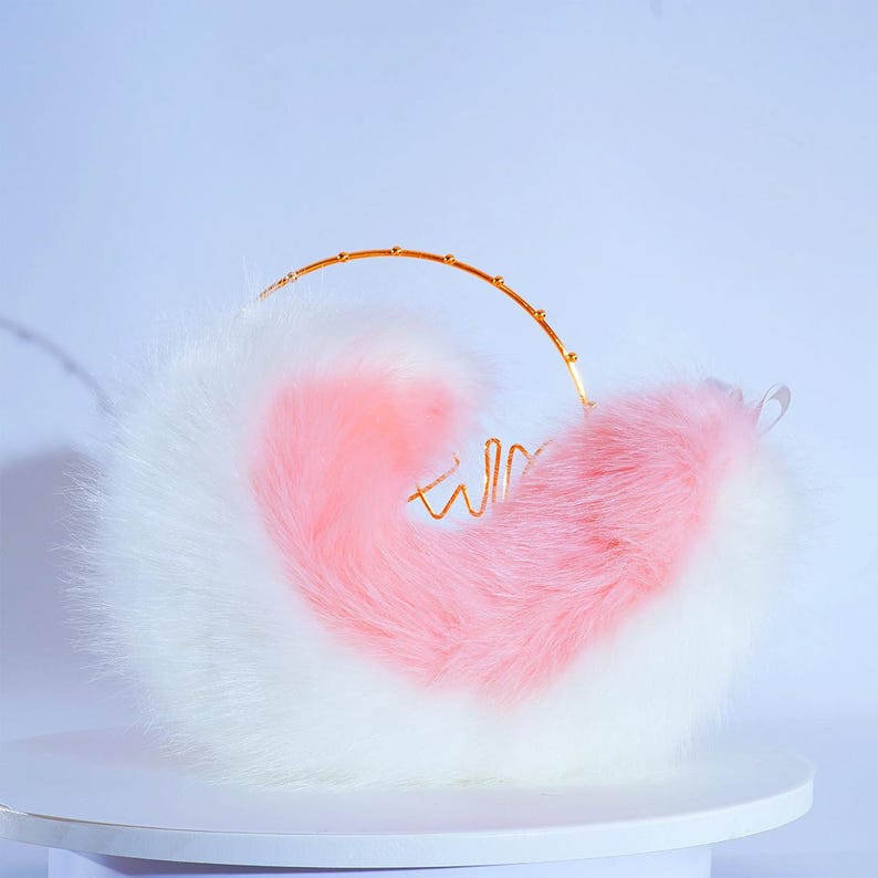 May include: A fluffy white and pink tail with a gold wire hoop. The tail is curled into a heart shape.