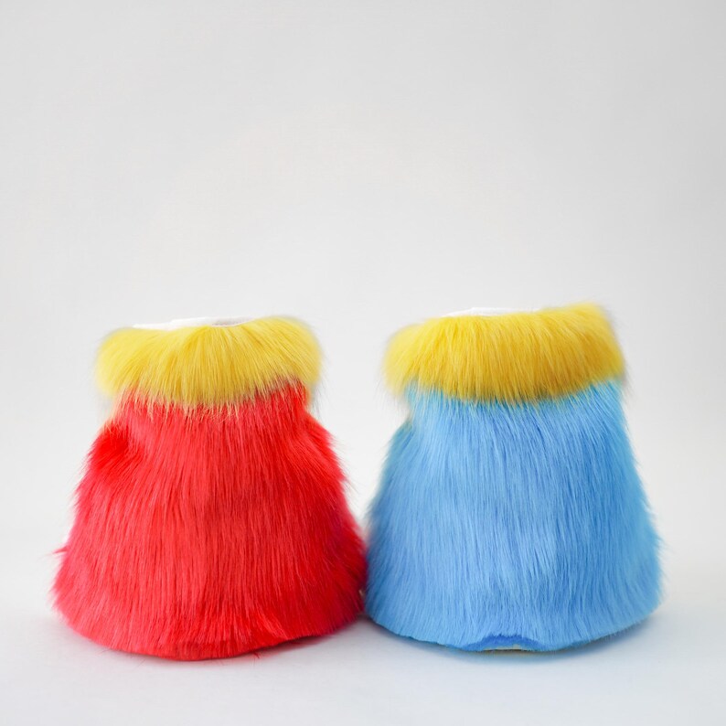 K&ouml;nnte beinhalten: Zwei farbenfrohe, flauschige Kunstfell-Stiefel&uuml;berzieher. Einer ist rot mit gelbem Oberteil, der andere blau mit gelbem Oberteil. Die Stiefel&uuml;berzieher sind ein lustiges und lebendiges Accessoire.