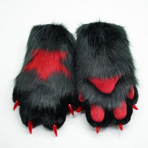 May include: A pair of black furry paws with red claws and red paw pads. The paws are designed to look like animal paws.