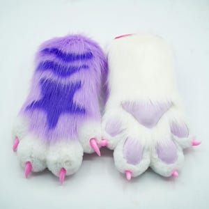 May include: A pair of furry purple and white paw hand puppets with pink claws. The purple paw has a star design.