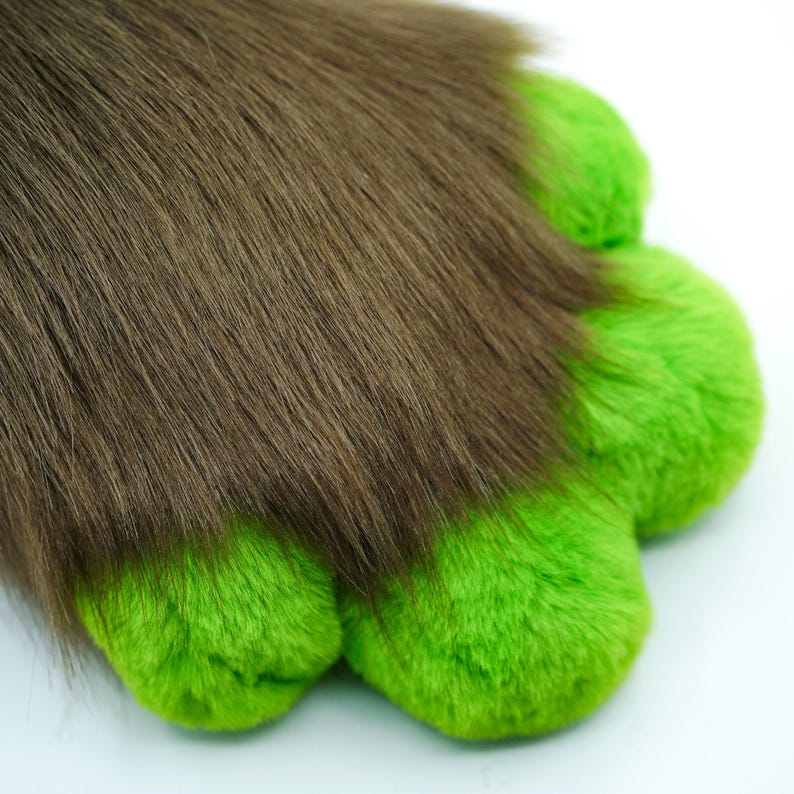 May include: A brown furry tail with green paw pads. The tail is soft and fluffy, and the paw pads are made of a plush material.