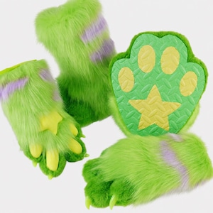 Op de afbeelding: Een set van felgroene kunstbont handpoten en een bijpassende voetpoot. De handpoten hebben lang groen bont met lichtpaarse strepen, gele klauwen en een gele ster op de palm. De voetpoot heeft een getextureerde groene zool met gele kussentjes.