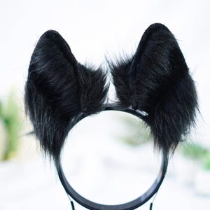 May include: Black furry cat ears headband. The headband is black and the ears are made of soft, fluffy black fur.