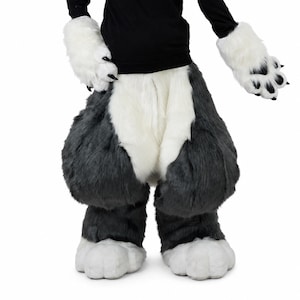 May include: A faux fur costume featuring dark grey and white plush leg coverings and matching white hand paws with black claws. The leg coverings have a thick, shaggy texture with a white central panel and dark grey sides, paired with white paw gloves.