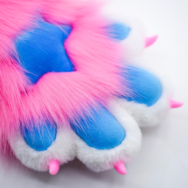 Puede incluir: Un par de patas peludas de color rosa y azul con garras blancas. Las patas est&aacute;n hechas de tela suave y afelpada y tienen un aspecto realista.