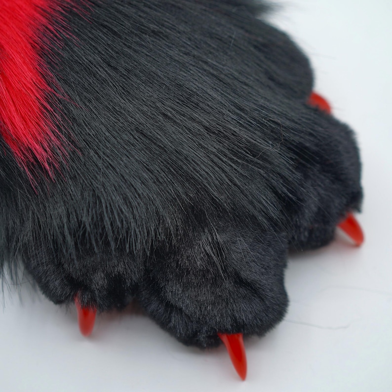 May include: Black and red furry paw with red claws. The paw is made of soft plush fabric and is designed to look like an animal paw.