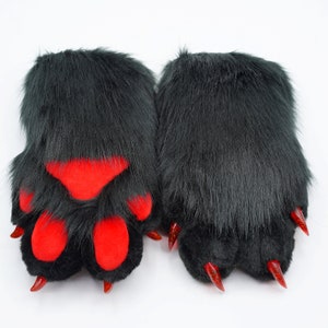 May include: A pair of black furry paw-shaped hand warmers with red paw pads and red claws.