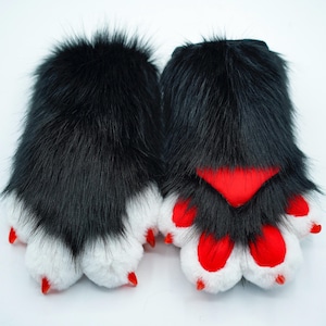 May include: A pair of black furry paw-shaped hand warmers with red claws and white fur accents.