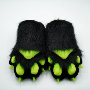 Puede incluir: Un par de marionetas de mano de piel negra con garras verdes. Las patas tienen un dise&ntilde;o tridimensional.