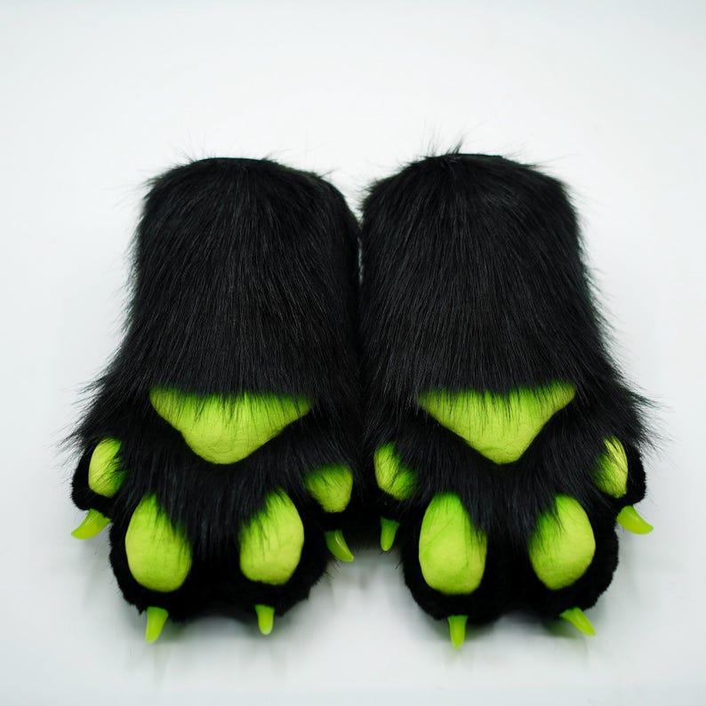 Puede incluir: Un par de marionetas de mano de piel negra con garras verdes. Las patas tienen un dise&ntilde;o tridimensional.