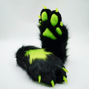 Puede incluir: Un par de patas peludas negras con garras y almohadillas de patas de color verde ne&oacute;n. Las patas est&aacute;n dise&ntilde;adas para parecer patas de animales.