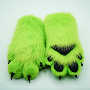 Op de afbeelding: Een paar felgroene, harige handpoppen met zwarte klauwen en zwarte voetzool.