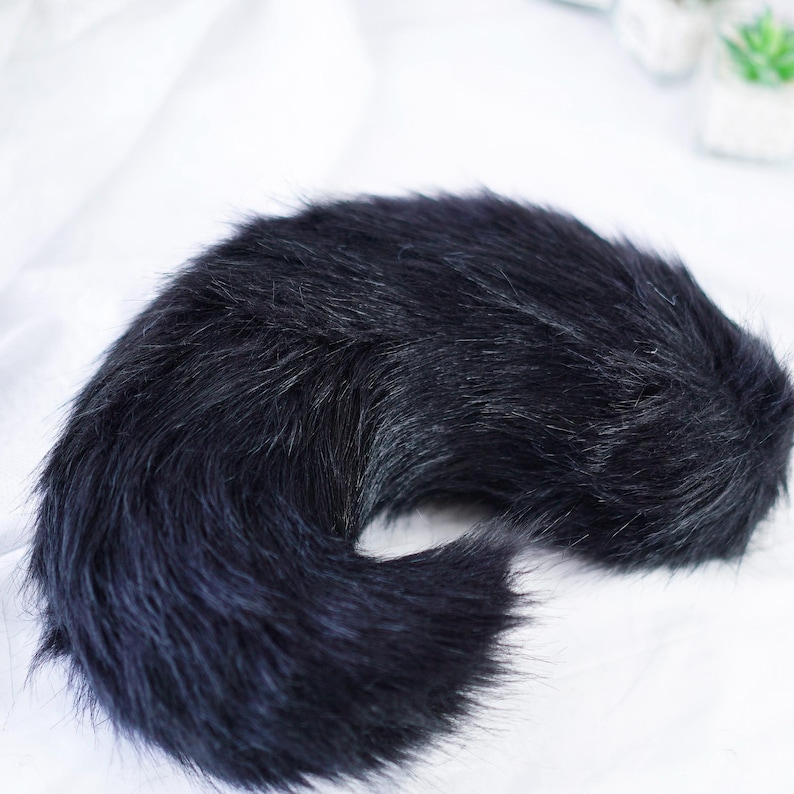 May include: A fluffy black faux fur tail with a long, curled shape. The tail is made of soft, plush material and is perfect for adding a touch of whimsy to any costume or outfit.