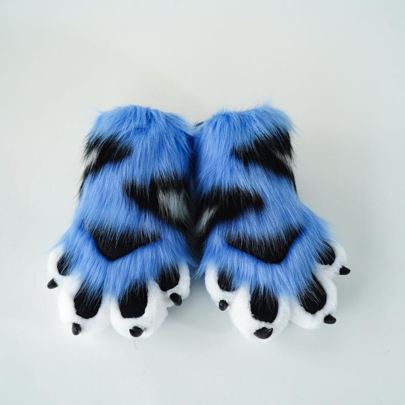 May include: A pair of blue and black faux fur paws with white paw pads and black claws. The furry paws are designed to resemble animal feet. The paws are set against a white background.