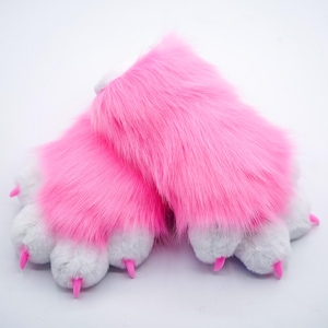 Puede incluir: Un par de marionetas de mano de color rosa con forma de pata, con garras blancas y garras de pl&aacute;stico rosa.