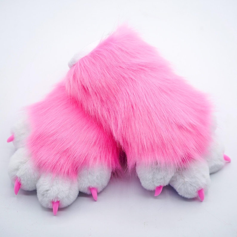 Puede incluir: Un par de marionetas de mano de color rosa con forma de pata, con garras blancas y garras de pl&aacute;stico rosa.