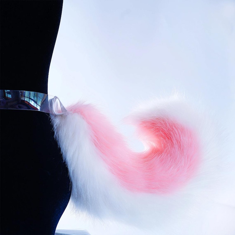 May include: A white and pink fluffy tail with a clear plastic band attached to the base.
