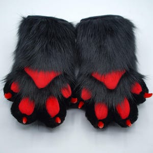 May include: A pair of black furry paw hand puppets with red paw pads and claws.