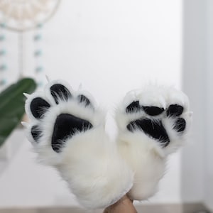 May include: A pair of white furry paw hand puppets with black paw pads and white claws.