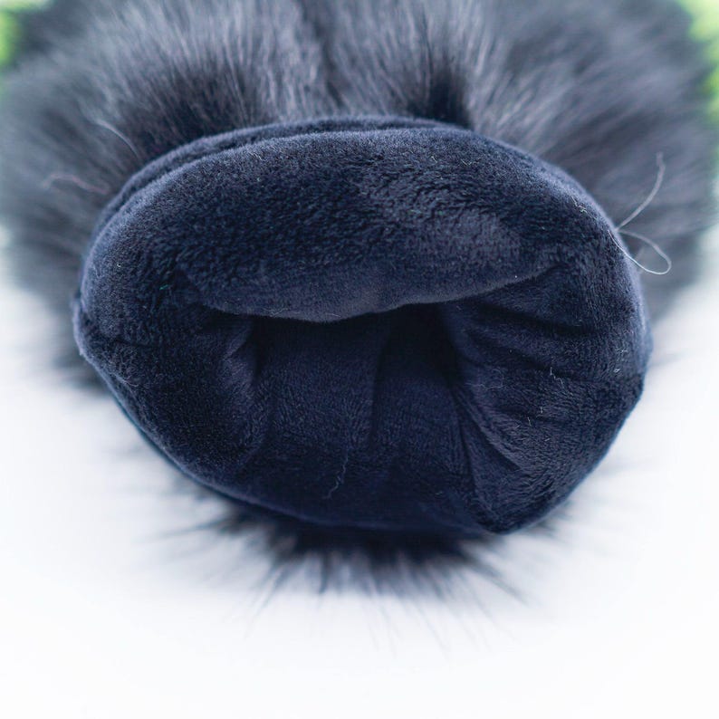 May include: Close-up of the inside of a black faux fur pom pom hat. The hat is lined with a soft, dark blue fleece fabric.