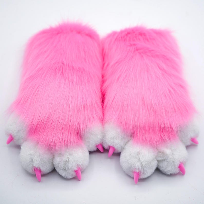 Puede incluir: Un par de pantuflas de pata peludas de color rosa con almohadillas de pata blancas y garras rosas.