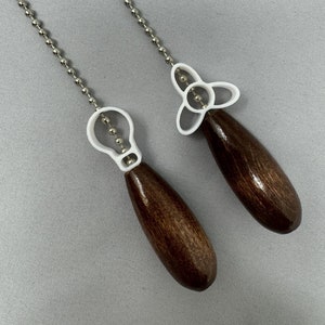 May include: Two brown wooden fan pull chains with white plastic lightbulb and fan blade designs.