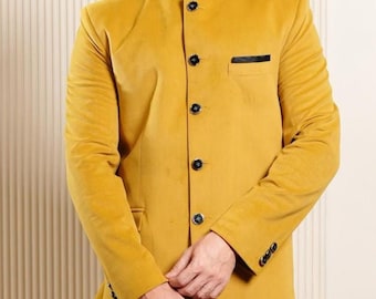 Könnte beinhalten: Senfgelber Samtblazer mit Stehkragen und schwarzen Knöpfen. Der Blazer wird mit einer schwarzen Anzughose und schwarzen Schuhen kombiniert. Ein klassisches, formelles Outfit.