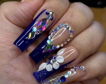 Uñas postizas con punta francesa azul y flores 3D, diseñadas en forma de cuadrado largo.