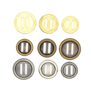 Könnte beinhalten: Sortiment aus zehn Metallknöpfen mit einem Doppelbalken-Design. Die Knöpfe sind in drei verschiedenen Ausführungen erhältlich: Gold, Messing und Silber.