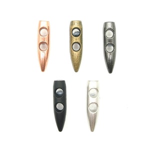 May include: Five metal bullet-shaped toggles in different finishes: gold, brass, silver, black, and nickel. Each toggle has two holes for threading cord or string.