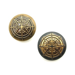 May include: Two round metal buttons with a compass rose design. One button is gold with a black compass rose, and the other is black with a gold compass rose.