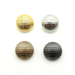 May include: Four round buttons with a grid pattern. The buttons are gold, silver, brass, and black.