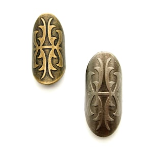 May include: Two oval-shaped metal rings with a decorative design. The rings are both silver in colour, but one has a gold-toned finish.