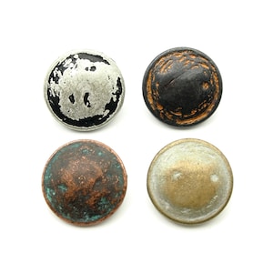 Könnte beinhalten: Vier runde Metallknöpfe mit abgenutzten Oberflächen. Die Knöpfe sind silber, schwarz, kupferfarben und goldfarben.