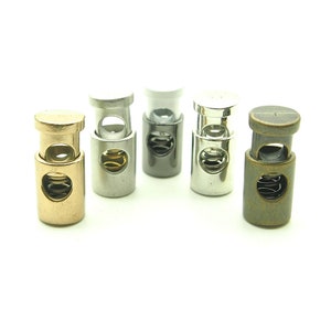 May include: Five metal cord stoppers in different finishes: gold, silver, black, chrome, and antique brass. Each stopper has a spring mechanism to adjust the cord length.