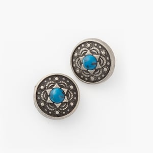 Könnte beinhalten: Zwei silberfarbene Knöpfe mit einem blauen Türkis-Stein in der Mitte. Die Knöpfe haben ein dekoratives Design um den Stein herum.