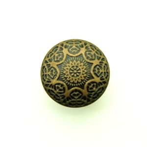 Peut inclure: Un bouton rond décoratif avec un motif noir et or. Le bouton présente un motif complexe et en relief de fleurs et de volutes.