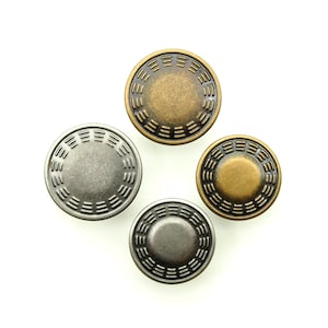Pode incluir: Quatro botões de metal com um design decorativo. Dois botões são prateados e dois botões são dourados.