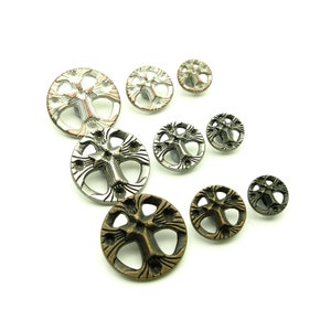 Könnte beinhalten: Sortiment von sieben Metallknöpfen mit Kreuzdesign. Die Knöpfe sind in verschiedenen Größen und Ausführungen erhältlich, darunter Silber, Gold und Kupfer.