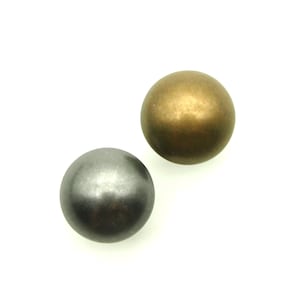 Op de afbeelding: Twee ronde metalen knopen, een gouden en een zilveren. De knopen zijn glad en glanzend.