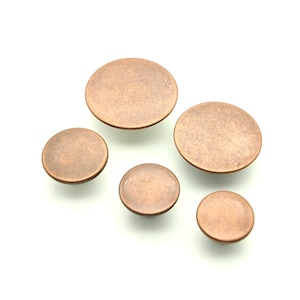 May include: Five round, copper-coloured metal buttons of varying sizes. The buttons have a slightly textured surface.