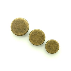 May include: Three round, metallic buttons in different sizes. The buttons are a gold color with a textured finish.