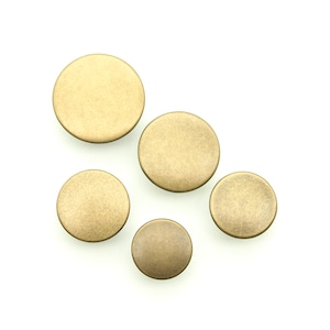 May include: Five round, brass-coloured buttons of varying sizes. The buttons have a slightly textured surface.