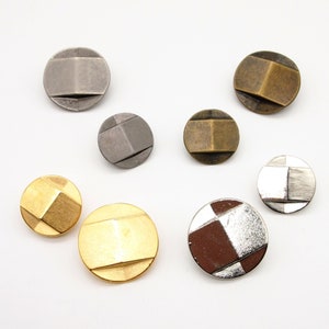May include: Assortment of eight metal buttons in various colors and designs. The buttons are round and have a geometric pattern. The colors include gold, silver, and bronze.