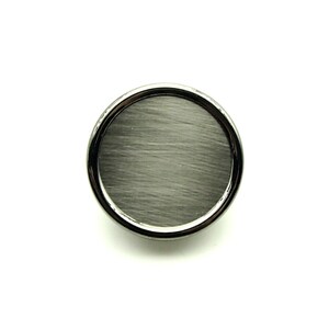 May include: A round, brushed nickel cabinet knob with a silver-toned border.