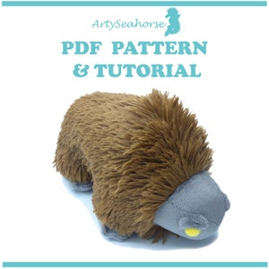 May include: A brown and grey plush toy resembling an echidna. The toy has a long snout and small, yellow eyes. The toy is lying on its belly with its legs tucked underneath it. The toy is made of soft, fuzzy fabric.