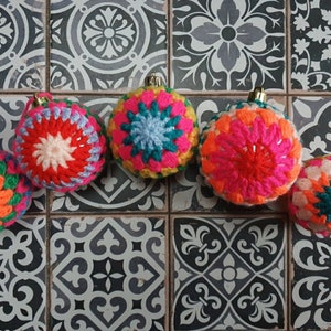 K&ouml;nnte beinhalten: Sechs bunte geh&auml;kelte Weihnachtskugeln mit verschiedenen Mustern und Farben, darunter Rosa, Rot, Orange, Gelb, Gr&uuml;n, Blau und Wei&szlig;.