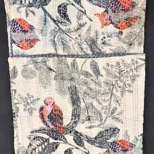 May include: A white cotton fabric with a repeating pattern of gray and red birds, leaves, and branches. The fabric is quilted with white thread.